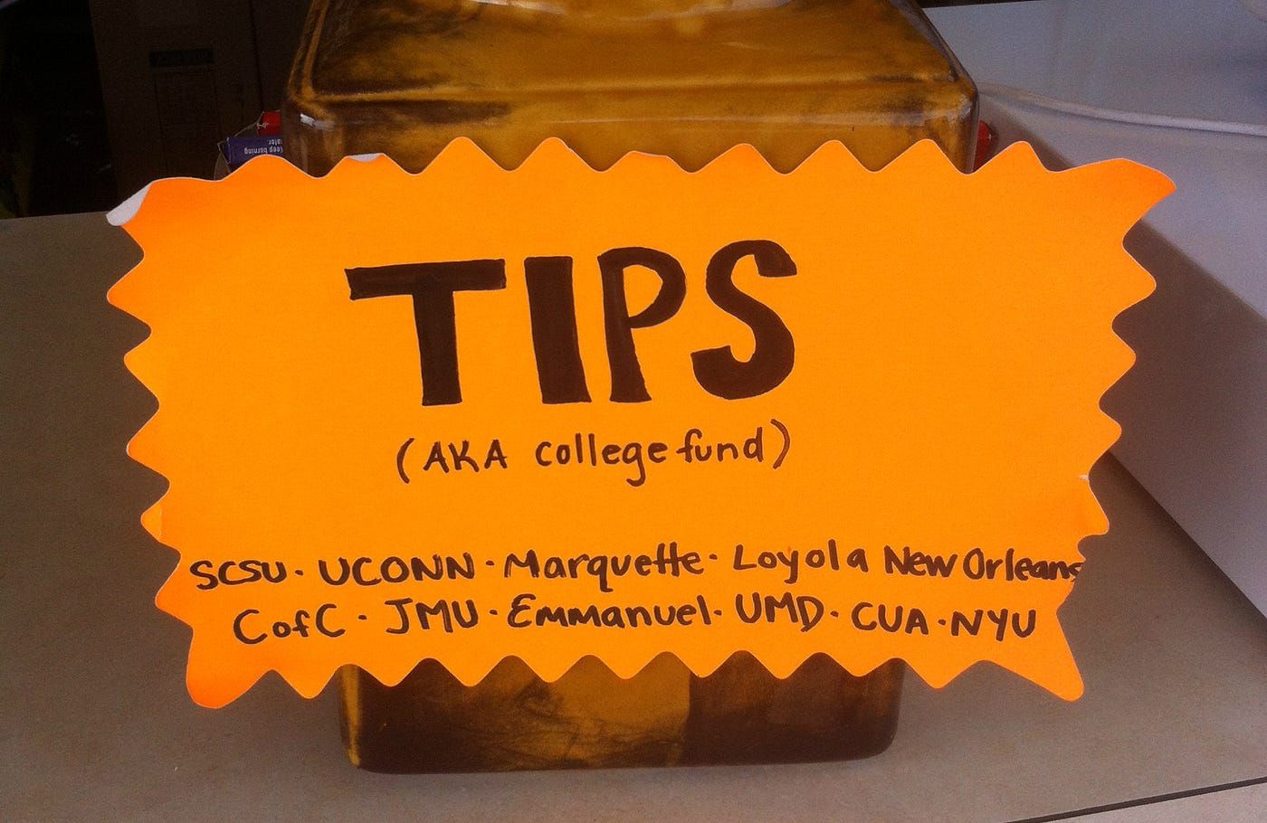 Tip jar with an orange paper and black text