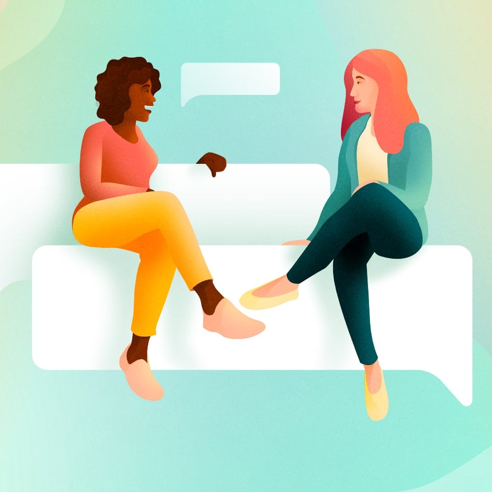 Two women talking while sitting on a speech bubble couch
