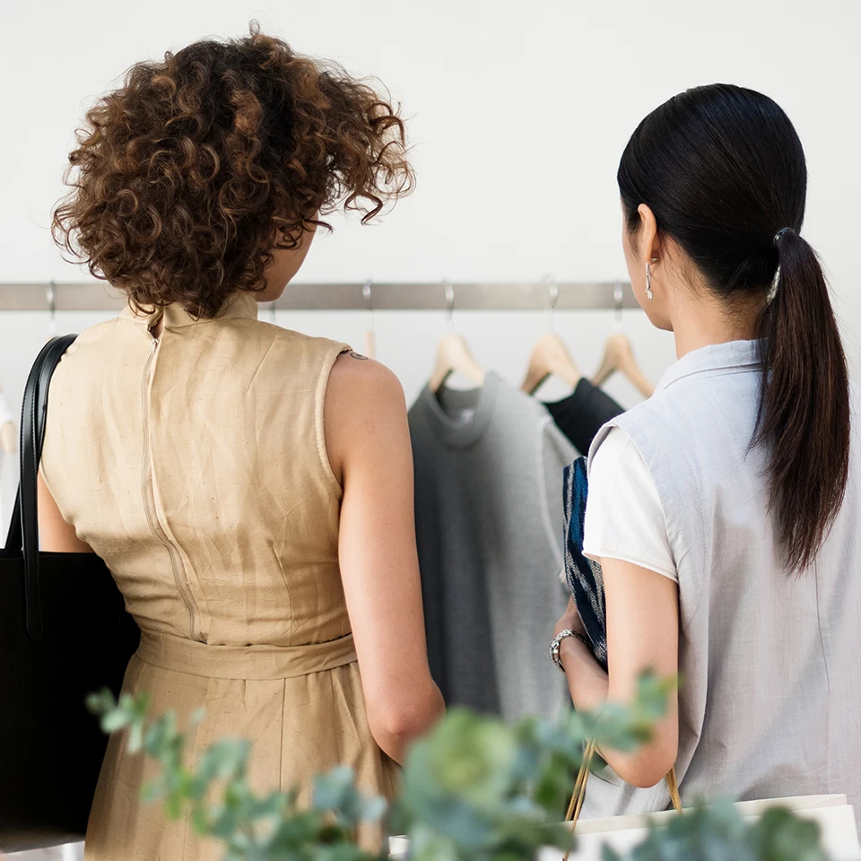 Two women looking at a rack of clothes in a shop